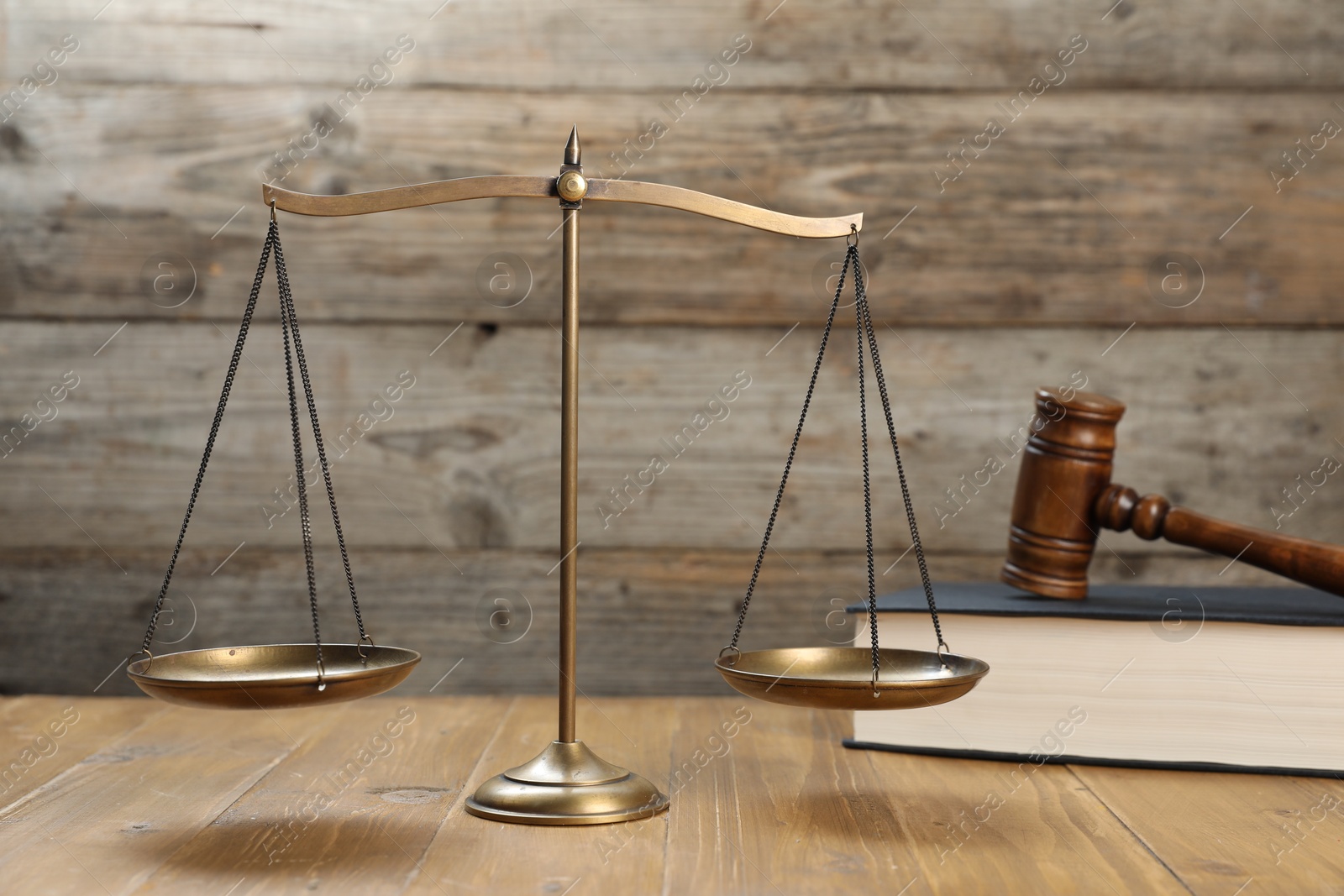 Photo of Scales of justice, gavel and book on wooden table, selective focus