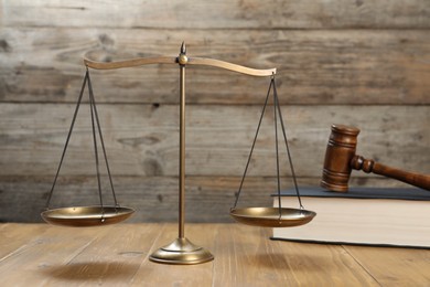 Photo of Scales of justice, gavel and book on wooden table, selective focus