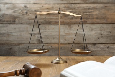 Photo of Scales of justice, gavel and book on wooden table, selective focus