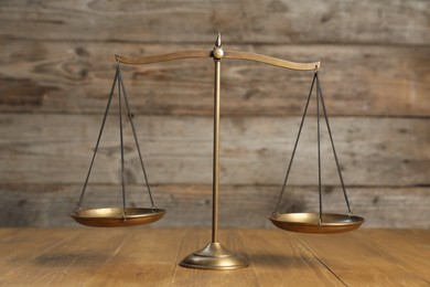 Photo of Golden scales of justice on wooden table