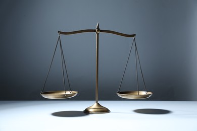 Photo of Golden scales of justice on grey background