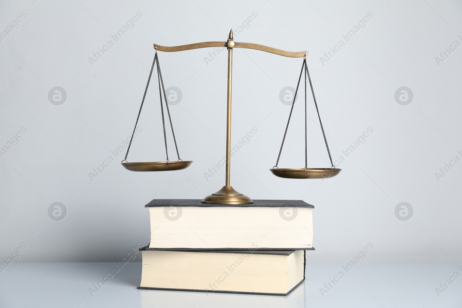 Photo of Scales of justice and books on light grey background