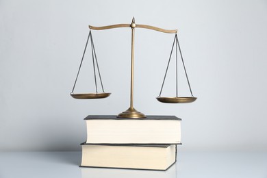 Photo of Scales of justice and books on light grey background