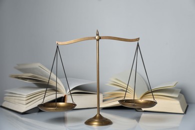 Photo of Scales of justice and books on light grey background