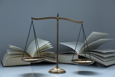 Photo of Scales of justice and books on grey background
