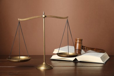 Photo of Scales of justice, gavel and book on wooden table, selective focus