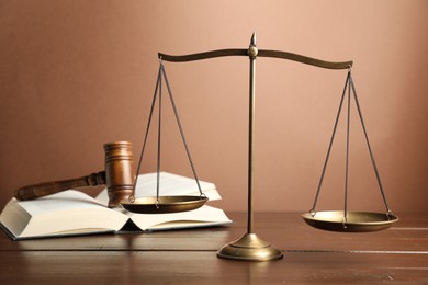 Photo of Scales of justice, gavel and book on wooden table, selective focus