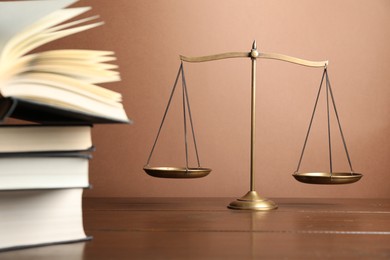 Photo of Scales of justice and books on wooden table