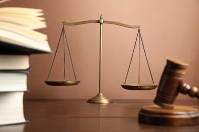 Photo of Scales of justice, gavel and books on wooden table, selective focus