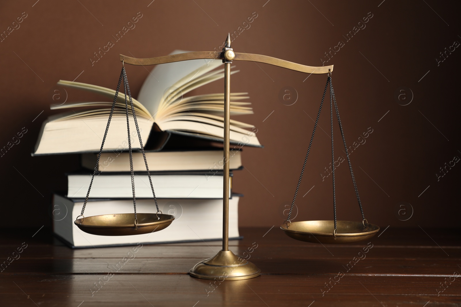 Photo of Scales of justice and books on wooden table