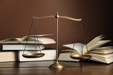Photo of Scales of justice and books on wooden table