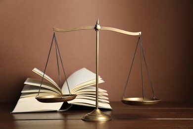 Photo of Scales of justice and book on wooden table