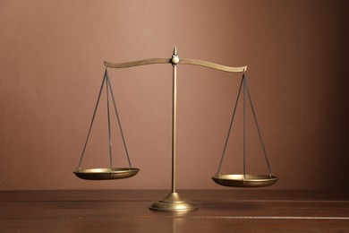 Photo of Golden scales of justice on wooden table