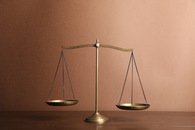 Photo of Golden scales of justice on wooden table