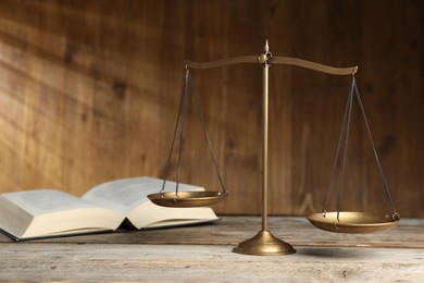 Photo of Scales of justice and book on wooden table