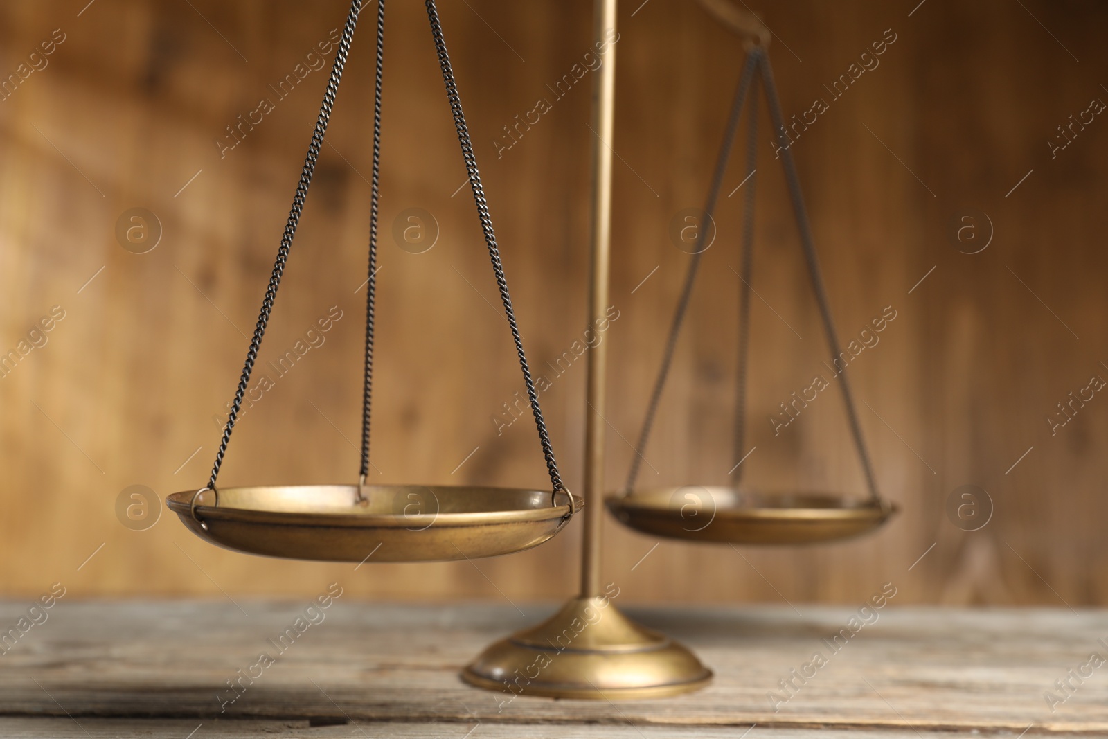 Photo of Golden scales of justice on wooden table, closeup