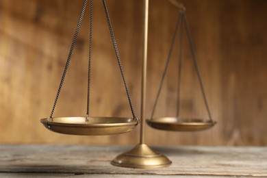 Photo of Golden scales of justice on wooden table, closeup