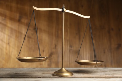 Photo of Golden scales of justice on wooden table