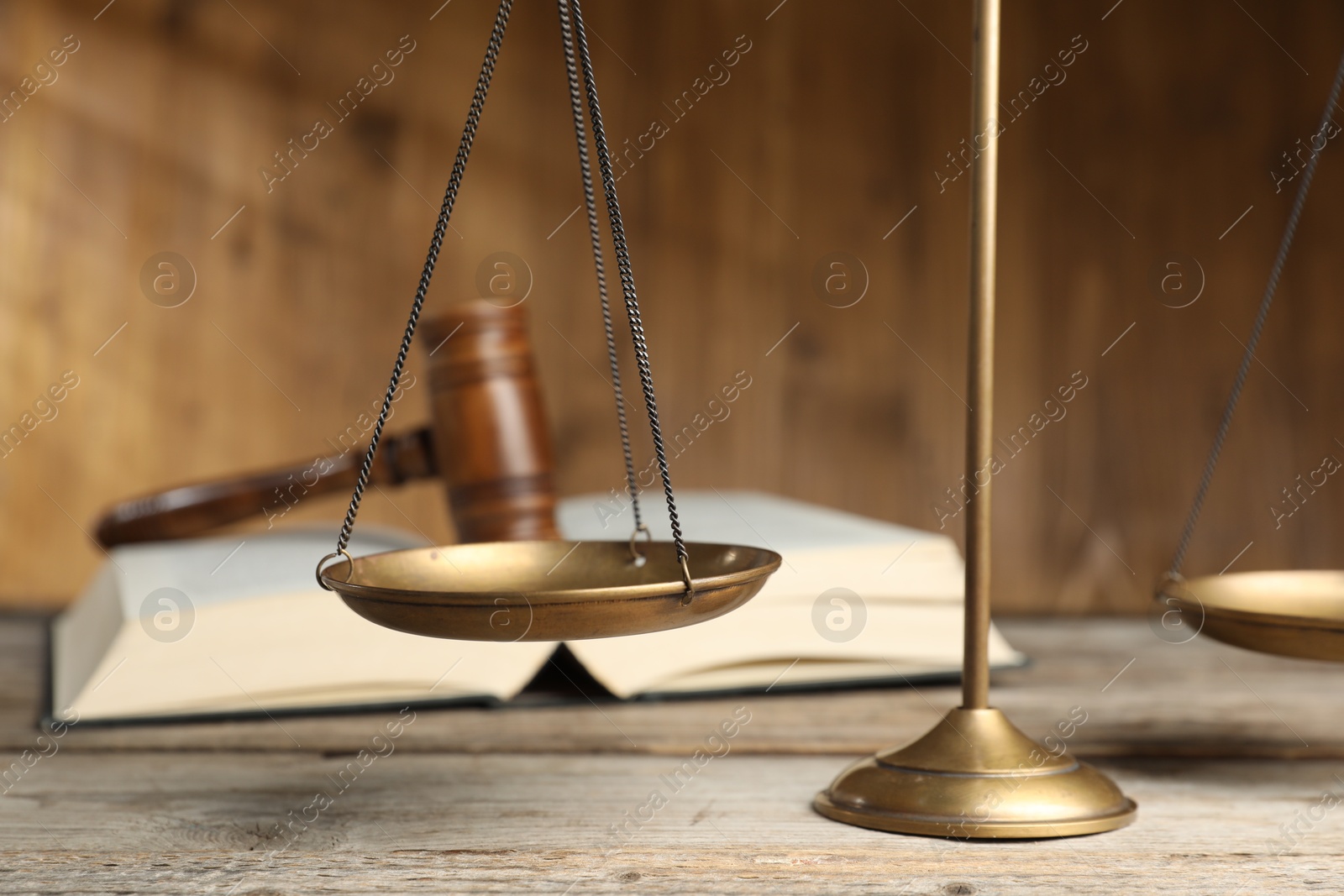 Photo of Scales of justice, gavel and book on wooden table, selective focus