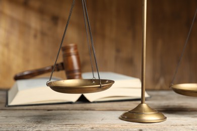 Photo of Scales of justice, gavel and book on wooden table, selective focus