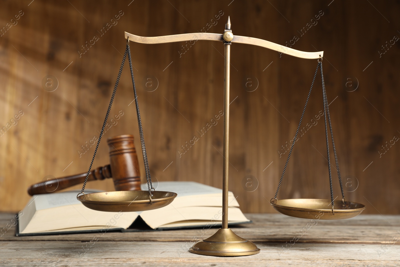 Photo of Scales of justice, gavel and book on wooden table, selective focus