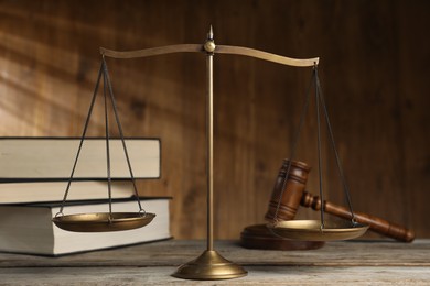 Photo of Scales of justice, gavel and books on wooden table, selective focus