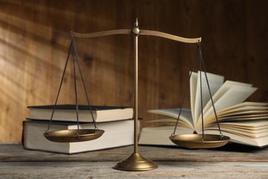Photo of Scales of justice and books on wooden table