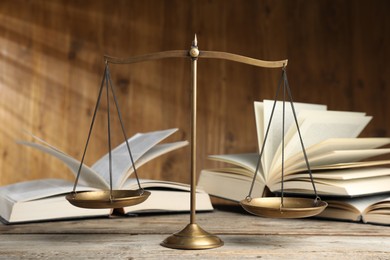 Photo of Scales of justice and books on wooden table