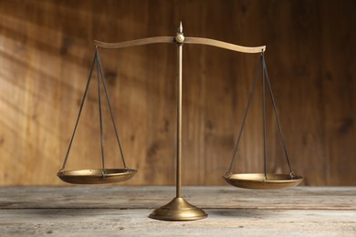 Photo of Golden scales of justice on wooden table