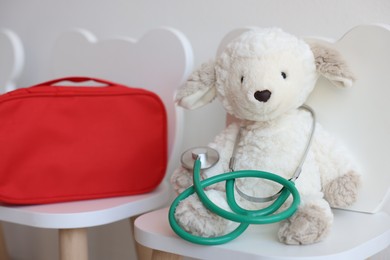 Photo of Pediatrician concept. Toy sheep, medical bag and stethoscope on chairs in clinic