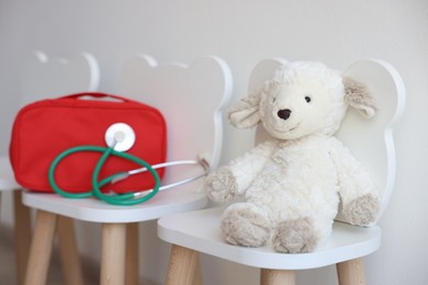 Photo of Pediatrician concept. Toy sheep, medical bag and stethoscope on chairs in clinic