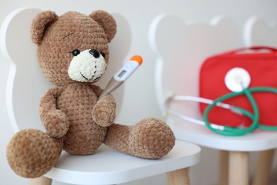 Photo of Pediatrician concept. Toy bear, thermometer, medical bag and stethoscope on chairs in clinic, closeup