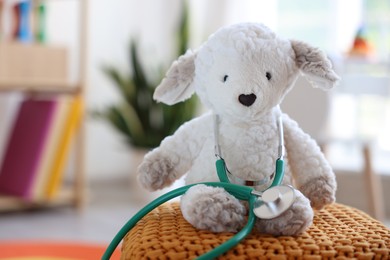 Photo of Pediatrician concept. Toy sheep and stethoscope on pouf in clinic, closeup