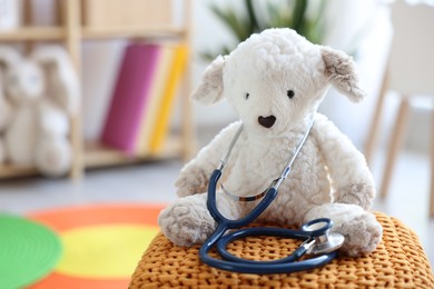 Photo of Pediatrician concept. Toy sheep and stethoscope on pouf in clinic, closeup. Space for text