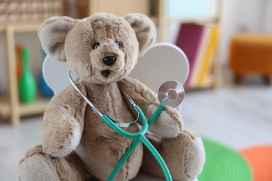 Photo of Pediatrician concept. Toy bear and stethoscope on chair in clinic, closeup