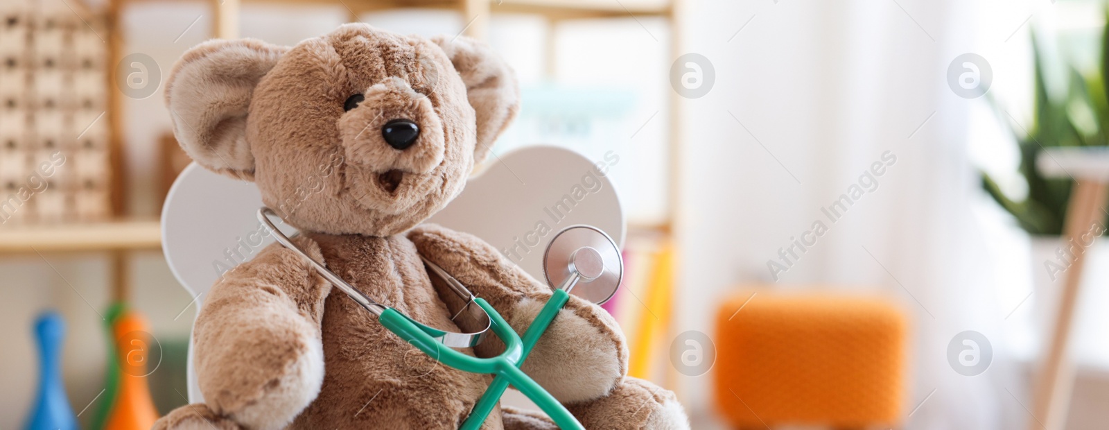 Photo of Pediatrician concept. Toy bear and stethoscope on chair in clinic, closeup. Space for text