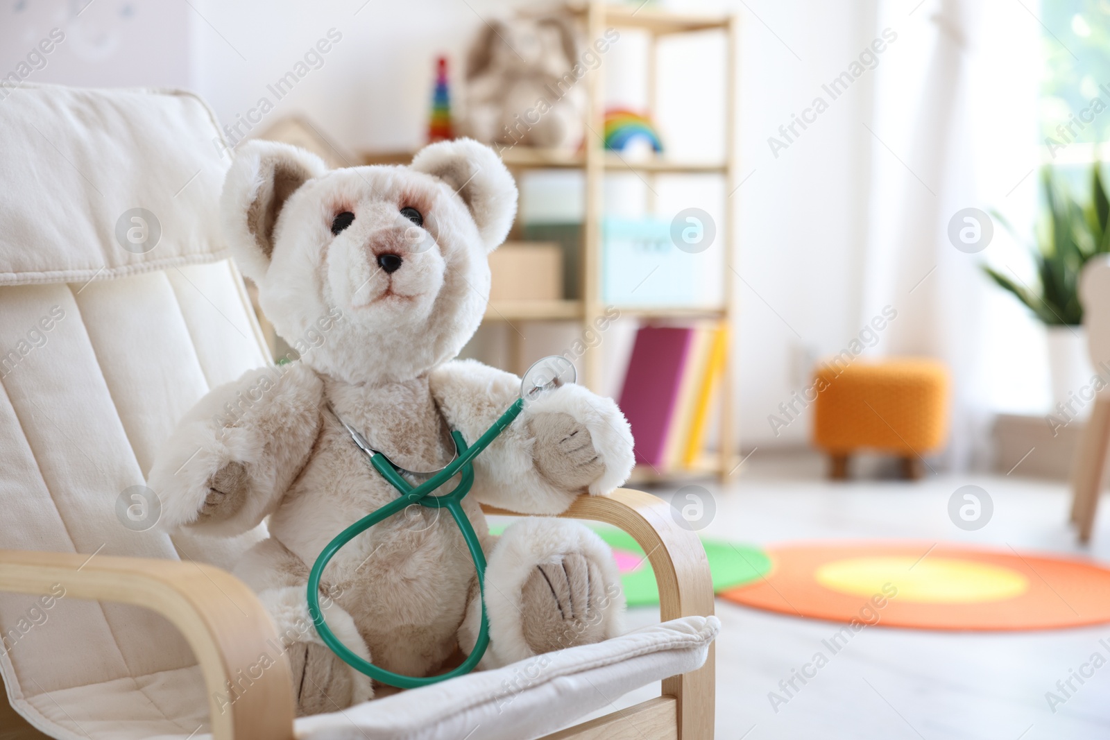 Photo of Pediatrician concept. Toy bear and stethoscope on armchair in clinic, space for text