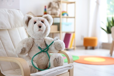 Photo of Pediatrician concept. Toy bear and stethoscope on armchair in clinic, space for text