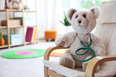 Photo of Pediatrician concept. Toy bear and stethoscope on armchair in clinic, space for text
