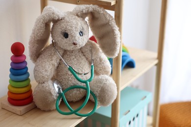 Photo of Pediatrician concept. Toys and stethoscope on wooden shelves in clinic, closeup. Space for text