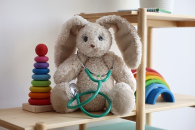 Photo of Pediatrician concept. Toys and stethoscope on wooden shelves in clinic, closeup