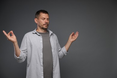 Photo of Panic attack. Man meditating to calm down on grey background, space for text