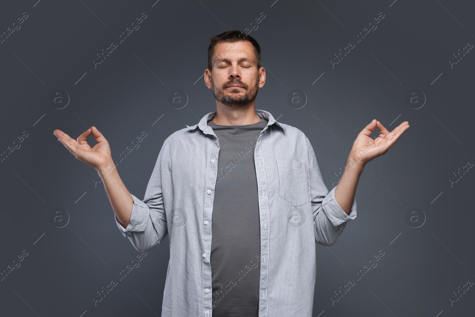 Panic attack. Man meditating to calm down on grey background Photo of Panic attack. Man meditating to calm down on grey background