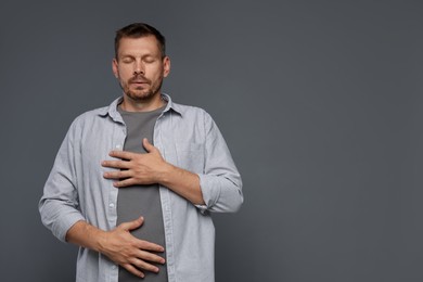 Photo of Panic attack. Man breathing to calm down on grey background, space for text