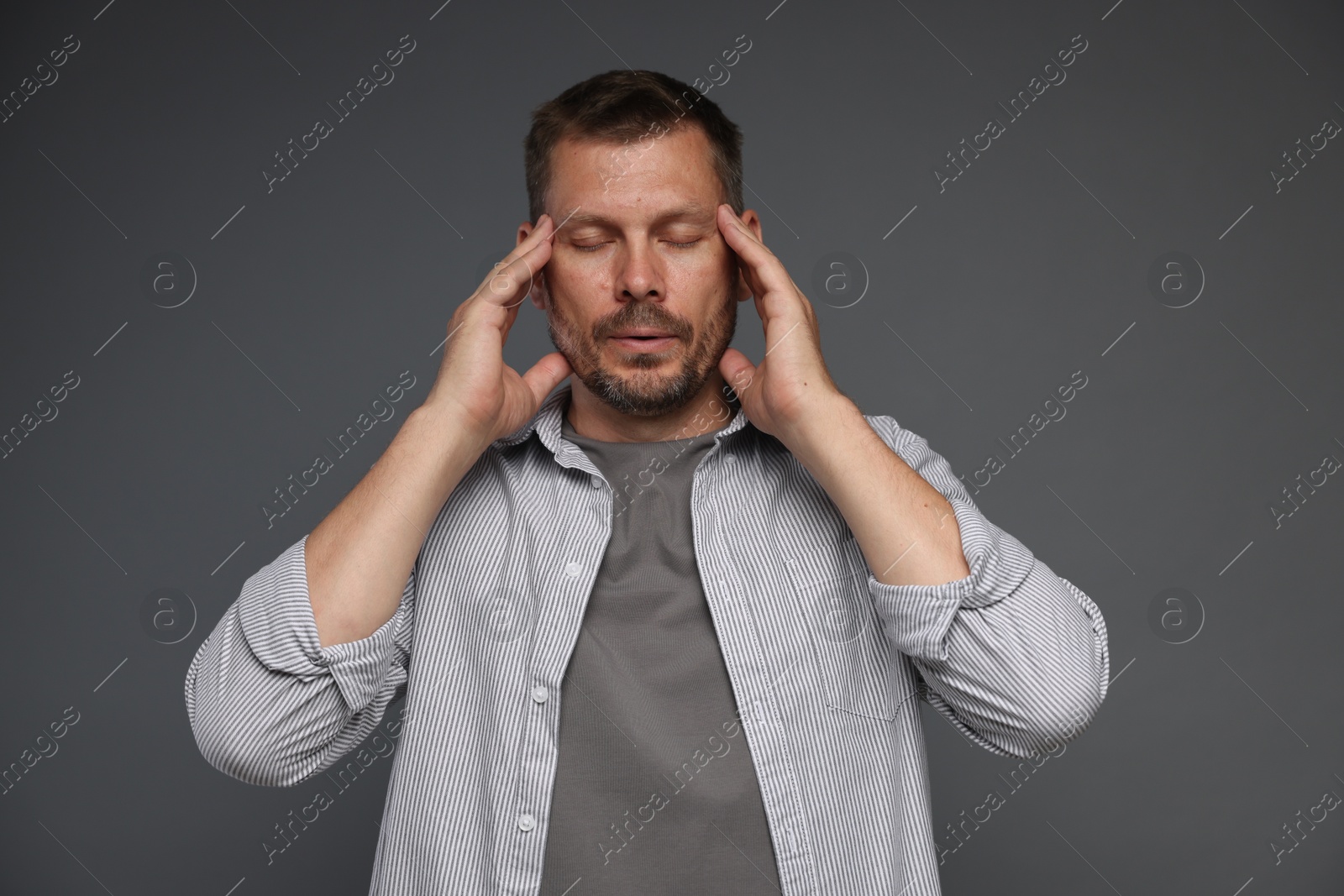 Panic attack. Man calming himself down on grey background Photo of Panic attack. Man calming himself down on grey background