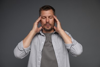 Photo of Panic attack. Man calming himself down on grey background