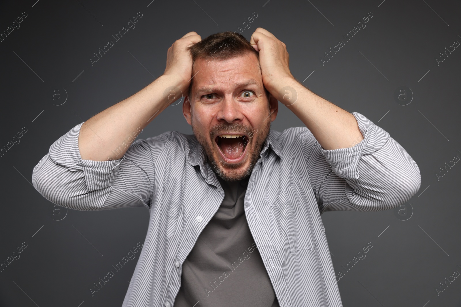 Man suffering from panic attack on grey background Photo of Man suffering from panic attack on grey background