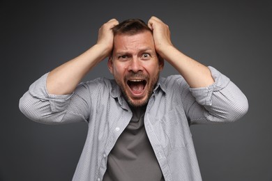 Photo of Man suffering from panic attack on grey background