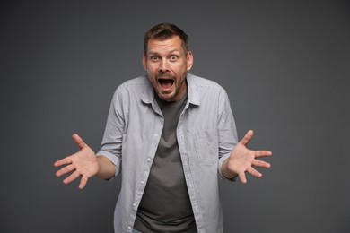 Photo of Man suffering from panic attack on grey background