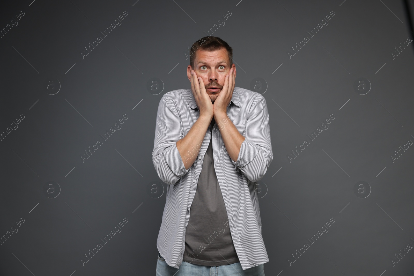 Photo of Man suffering from panic attack on grey background